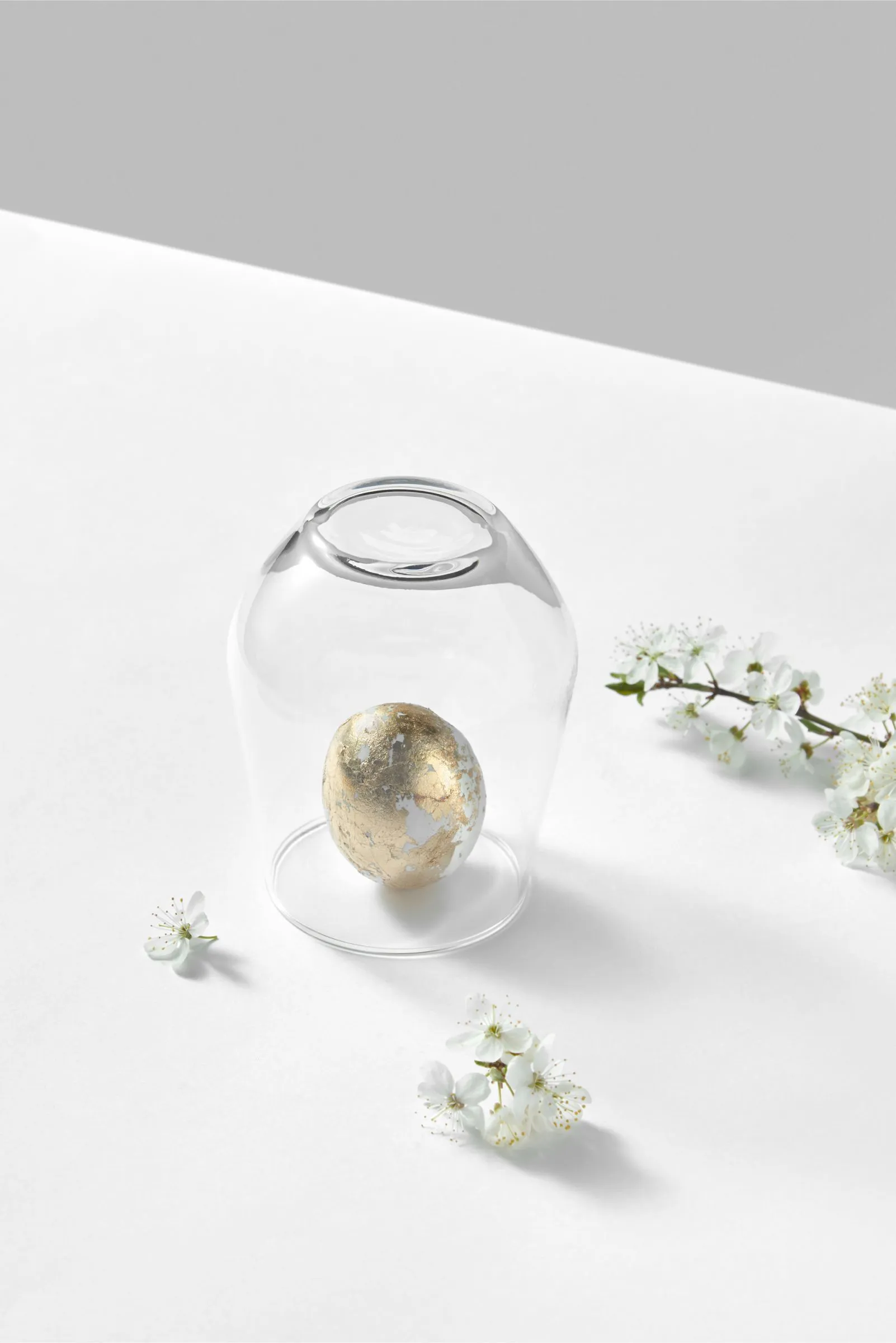 Gold speckled egg under glass dome with flowers.